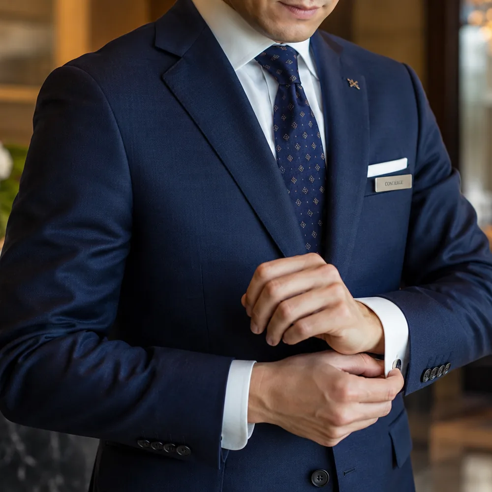 Bespoke navy concierge uniform jacket with house badge and working cuff buttons, tailored by Noble Fox