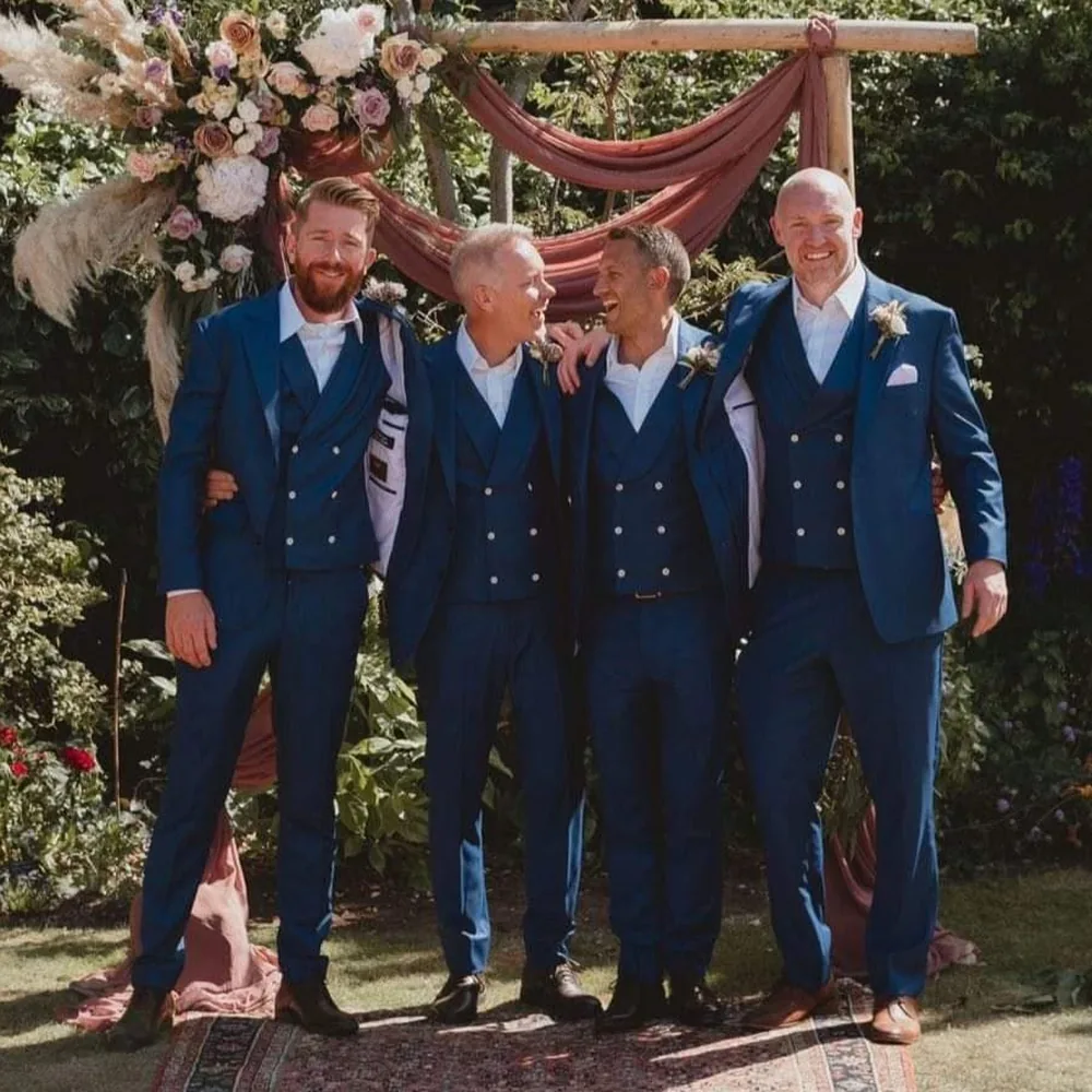 Four groomsmen in bespoke blue double-breasted waistcoat suits at a garden wedding
