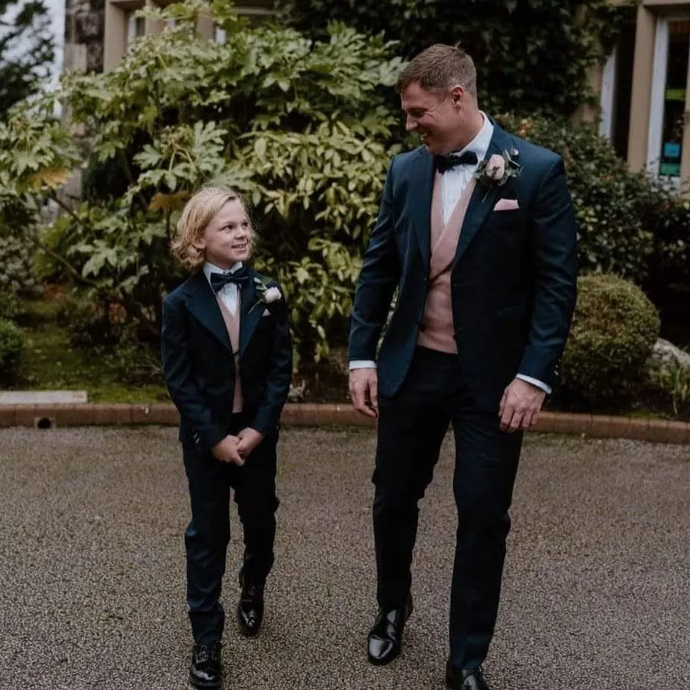 Groom and young page boy in matching navy dinner jackets with blush waistcoats